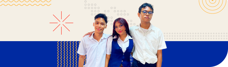 Foto de tres jóvenes posando juntos frente a un fondo decorativo. En el centro, una joven con gafas y cabello largo oscuro lleva una camisa blanca y chaleco azul marino, sonriendo ligeramente. A su izquierda, un joven de cabello corto con camisa blanca le rodea el hombro, también sonriendo. A la derecha, otro joven con gafas y expresión seria usa una camisa blanca. El fondo combina patrones gráficos en colores como azul, amarillo y rojo, con líneas onduladas, círculos y otros elementos geométricos sobre una base beige en la parte superior y azul en la inferior.