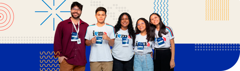 Grupo de estudantes e educador do IEMA com crachás, sorrindo em evento educacional