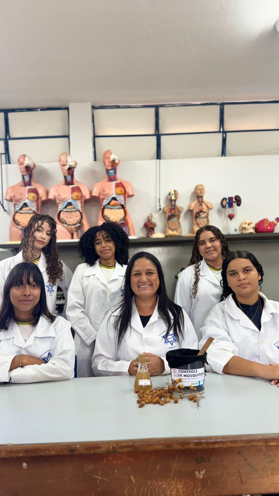 Grupo em laboratório escolar com materiais sobre controle da dengue