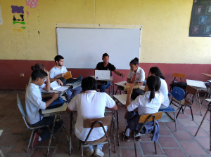 Estudantes participam de atividade colaborativa com computador e materiais didáticos em sala de aula
